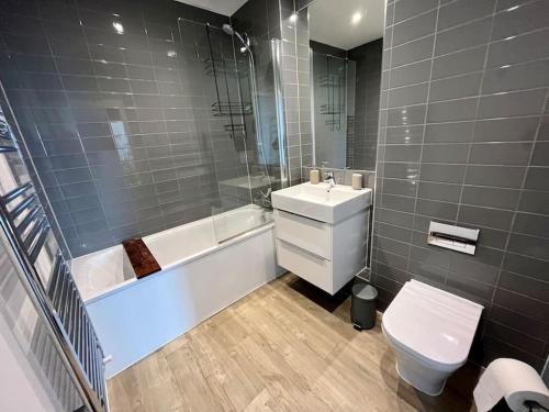 La salle de bains est pourvue d'un lavabo, d'une baignoire et de toilettes. dans l'établissement Elegant Chic Living: 1 Bed In Vibrant London Area, à Londres