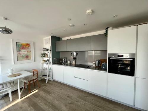 a kitchen with white cabinets and a white table and a table at Elegant Chic Living: 1 Bed In Vibrant London Area in London