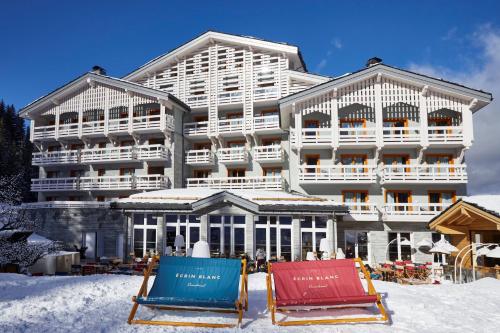 a hotel in the snow with two chairs in front of it at Ecrin Blanc Resort Courchevel - Aquapark in Courchevel
