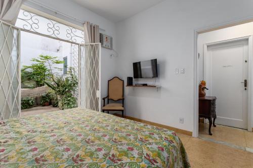 um quarto com uma cama, uma janela e uma televisão em STUDIOS URCA na rua da mureta da Urca no Rio de Janeiro