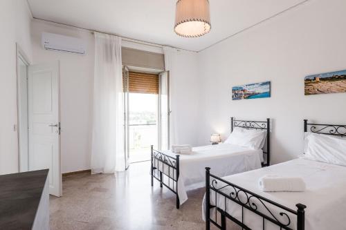 2 camas en una habitación blanca con ventana en Casa Adda by Wonderful Italy, en Siracusa
