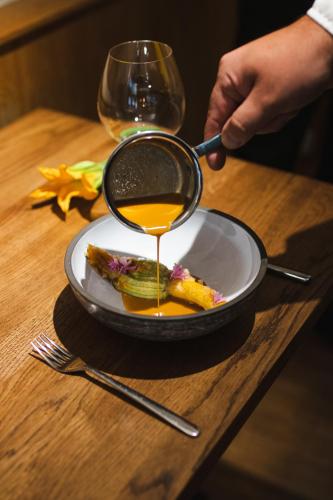 a person is pouring honey onto a plate of food at Dome Hotel in Rīga