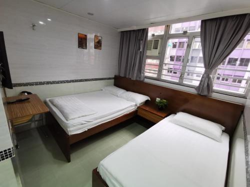 two beds in a small room with two windows at 香港百乐宾馆 Best-B&B in Hong Kong