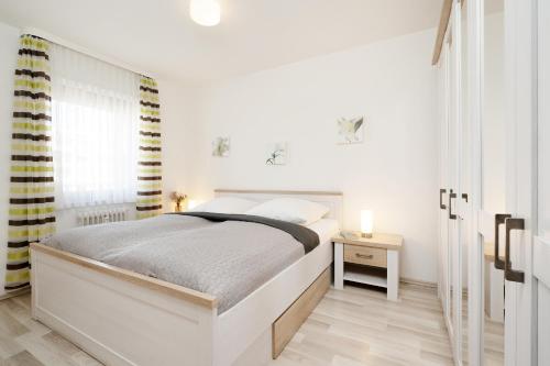 ein weißes Schlafzimmer mit einem Bett und einem Fenster in der Unterkunft Belvedere Ostseebrise in Grömitz
