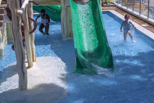 a group of children playing on a water slide at GHT Oasis Park & Spa in Lloret de Mar