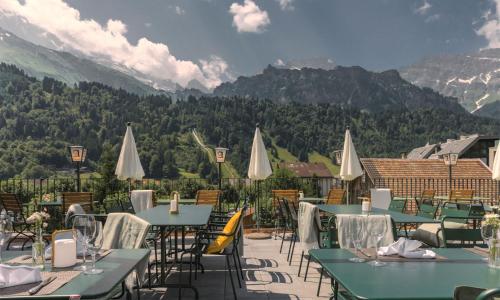a restaurant with tables and chairs with mountains in the background at Alpenclub in Engelberg