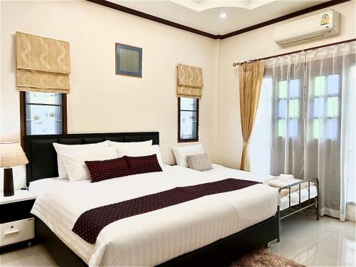 a bedroom with a large bed and windows at Malinee Villa Phuket in Bang Tao Beach