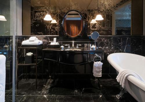 a bathroom with a sink and a tub and a mirror at Hotel Muse Bangkok Langsuan - MGallery in Bangkok