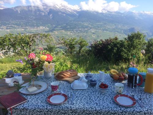 Domaine Bellevie BnB في Vex: طاولة عليها أطباق من الطعام والزهور