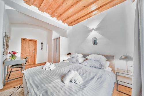 a white bedroom with a large bed with white pillows at Smile Apartments "Lesehof" in Krems an der Donau