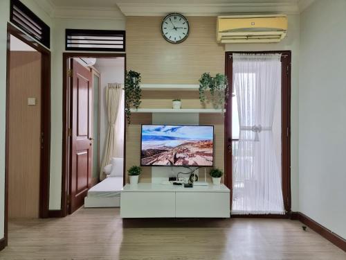 een woonkamer met een tv en een klok aan de muur bij Majesty Apartment 2 Bedroom with City View in Bandung