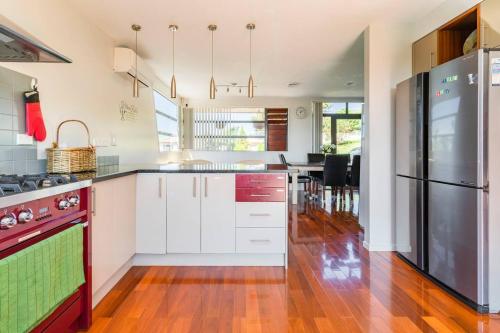 cocina con armarios blancos y nevera negra en Private room in a lovely house, en Auckland