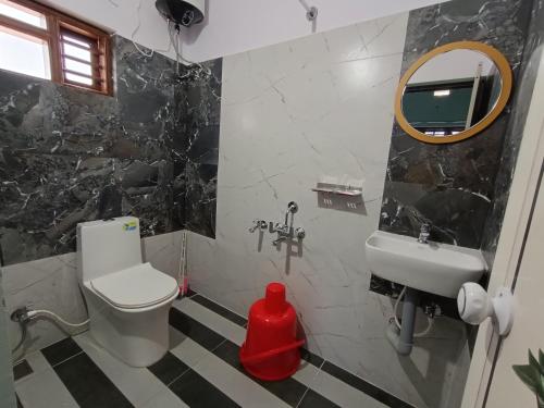 a bathroom with a sink and a toilet and a mirror at Hill View Retreat - Coorg in Madikeri