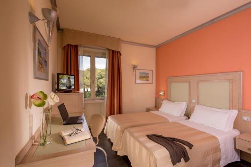 a hotel room with a bed and a desk with a laptop at Hotel Mediterraneo in Livorno