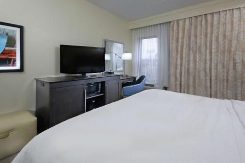 a hotel room with a bed and a flat screen tv at Hampton Inn High Point in Archdale
