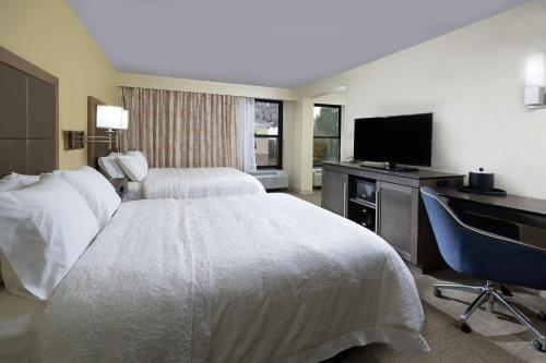 a hotel room with two beds and a flat screen tv at Hampton Inn High Point in Archdale