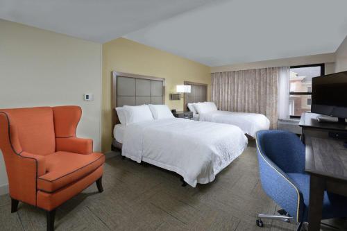 a hotel room with two beds and a chair and a television at Hampton Inn High Point in Archdale