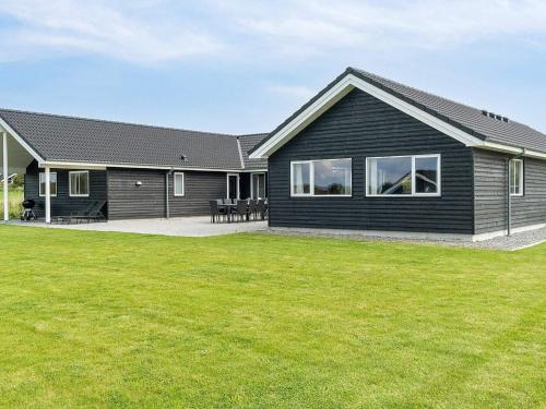 a black house with a green lawn in front of it at 20 person holiday home in Stege in Stege