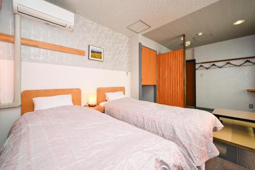 a bedroom with two beds and a desk with a desk at 栂池高原　丘の上ホテル in Otari
