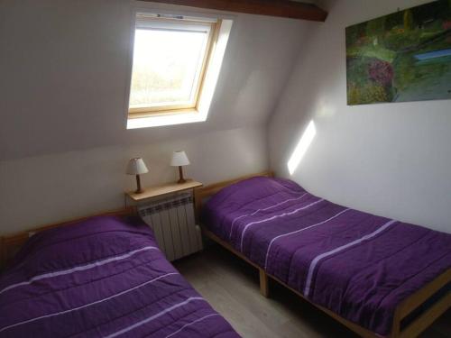 2 camas en una habitación con sábanas moradas y una ventana en Gîte Les Ronces, en Conteville