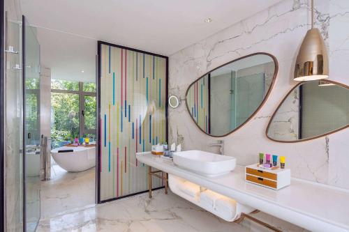 a bathroom with a sink and a mirror and a tub at Wingate by Wyndham Sanya Luhuitou in Sanya