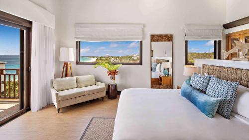 a bedroom with a bed and a couch and windows at Zemi Beach House, LXR Hotels & Resorts in Shoal Bay Village
