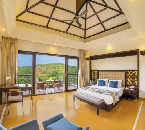 a bedroom with a large bed and a balcony at Mahua Bagh Resort Kumbhalgarh in Kumbhalgarh