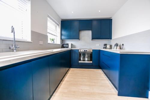 a kitchen with blue cabinets and a sink at Southern - Bracklesham Bay in Chichester
