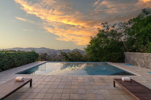 a swimming pool with a sunset in the background at Mahua Bagh Resort Kumbhalgarh in Kumbhalgarh