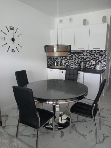 萊斯科的住宿－Apartament Bieszczadzka A 8 Lesko，餐桌、椅子和墙上的时钟