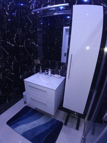 La salle de bains est pourvue d'un lavabo blanc et d'un miroir. dans l'établissement Apartament Bieszczadzka A 8 Lesko, à Lesko