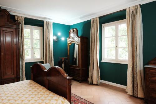 una camera da letto con pareti verdi, un letto e finestre di Villa Hélène a Solto Collina