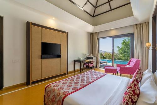 a bedroom with a bed and a tv and a pool at Mahua Bagh Resort Kumbhalgarh in Kumbhalgarh