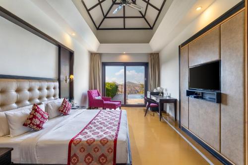 a hotel room with a bed and a flat screen tv at Mahua Bagh Resort Kumbhalgarh in Kumbhalgarh