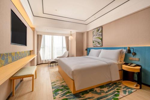 a hotel room with a bed and a desk at Hilton Garden Inn Guangzhou Airport Aerotropolis in Huadu