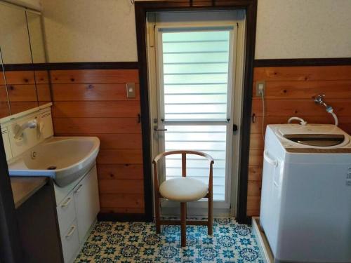 La salle de bains est pourvue d'une chaise, d'un lavabo et d'un lave-linge. dans l'établissement Greenwood Cottage Nikko, à Nikkō