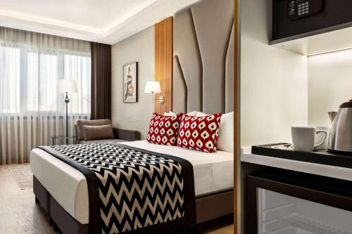 a hotel room with a bed with red and black pillows at Ramada Encore by Wyndham Istanbul Sisli in Istanbul