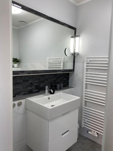 ein weißes Badezimmer mit einem Waschbecken und einem Spiegel in der Unterkunft Rehburger Landhaus in Rehburg-Loccum