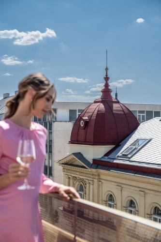 a woman in a pink dress holding a glass of wine at Almanac X Alcron Prague in Prague