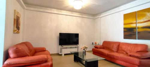 een woonkamer met twee rode banken en een flatscreen-tv bij John's house in Rhodos-stad
