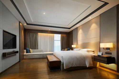 a bedroom with a large bed and a couch at Courtyard by Marriott Xinchang in Xinchang