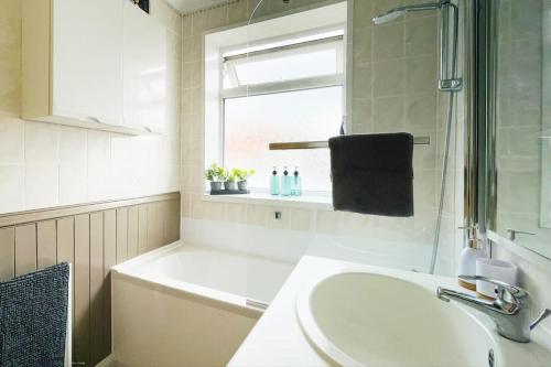 a bathroom with a sink and a bath tub and a window at Rose House, with garden, ideal for couples and families with easy parking in Kent