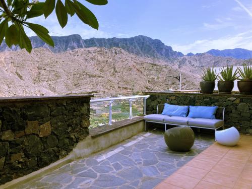a patio with blue pillows and a view of the mountains at Casa Julietta in Hermigua
