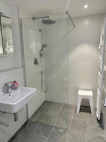 a white bathroom with a sink and a shower at Apartment Sonnenschwan - Neurenoviert, zentrumsnah und ruhig in Schliersee