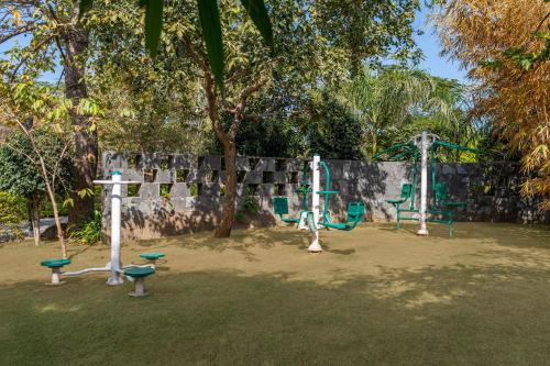a playground in a park with a tree and swings at Mahua Bagh Resort Kumbhalgarh in Kumbhalgarh