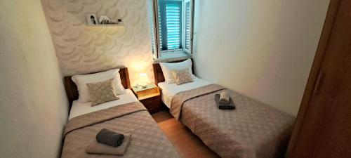 two twin beds in a room with a window at Stone House with garden Laganini in Zlarin