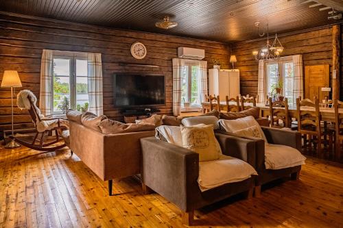 a living room with couches and a television in a room at Kotatuli Forest Lodge in Rovaniemi
