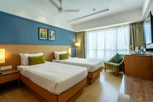 una habitación de hotel con 2 camas y una silla en GCC North Side en Bombay