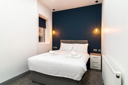 Un dormitorio con una gran cama blanca y una pared azul en Charnwood Flat 2 - 3BR Derby City Centre Flat en Derby
