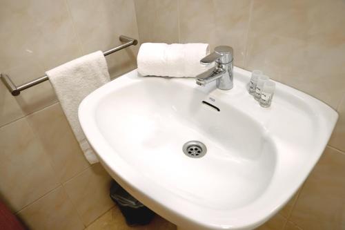 La salle de bains est pourvue d'un lavabo blanc et de serviettes. dans l'établissement Homenfun Barcelona Sagrada Familia Lepanto, à Barcelone